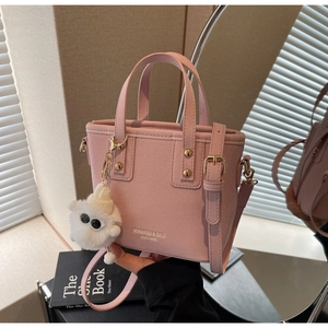 Detail of pink suede bucket bag with plush charm and Mikaxiqi logo print