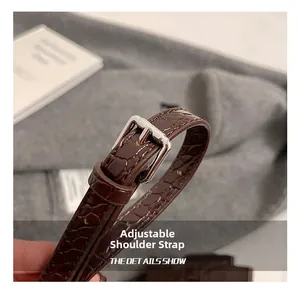 Dettaglio della tracolla marrone scuro testurizzata coccodrillo con fibbia d'argento