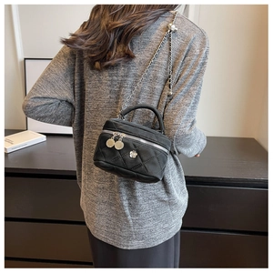 Detail of black quilted leather mini vanity bag with silver chain strap and floral charms