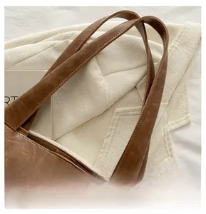Dettaglio borsa tote in pelle marrone scuro con cuciture di pregio sul manico