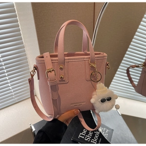 Pink suede bucket bag detail with gold logo lettering and plush lamb keychain