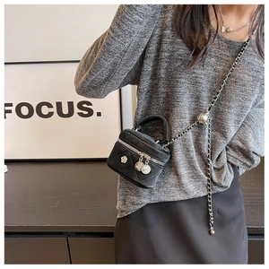 Detail of black quilted mini bag with adjustable gold-tone chain and flower charm