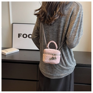 Close-up of a light pink quilted leather mini bag with chain strap worn by a model