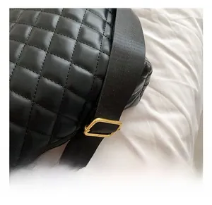 Detailed macro view of black quilted faux leather bag with gold metal buckle and strap