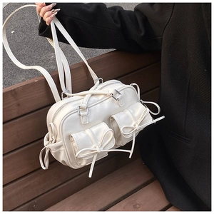 Detail of a creamy white Boston bag with bow pockets and silver metal buckles