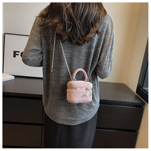 Detailed view of a pink quilted mini bag with a flower charm and metal chain strap