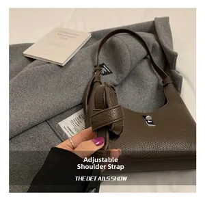 Dettaglio della borsa in pelle marrone scuro con chiusura a rotazione e tracolla