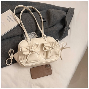 Detail of cream white faux leather underarm bag with decorative side bow accents