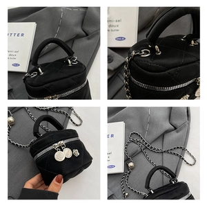 Detail view of black quilted mini bucket bag with silver chain strap and floral charms