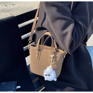 Detail of dark brown felt bucket bag with cute plush monster charm and adjustable strap