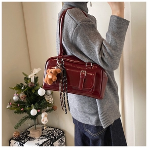Detail of burgundy patent leather bag with plush bear charm in a festive holiday setting