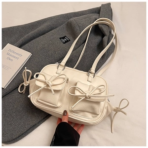 Close-up of cream Boston bag featuring decorative bow pockets and smooth leather texture