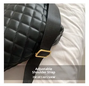 Detail of black quilted bag featuring an adjustable wide strap with gold metal buckle