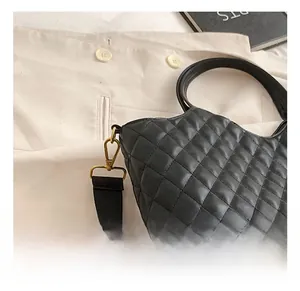 Detail shot of the golden metal hook and quilted leather texture of the black tote bag