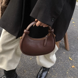 Minimalist brown crescent leather shoulder bag with decorative knotted handle and metal zipper
