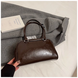 Detail of a dark brown glossy Boston bag with silver hardware and double handles