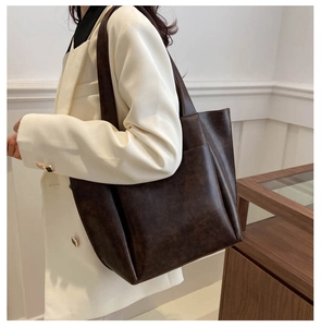 Dettaglio della grande borsa tote marrone con texture in pelle e tasca laterale indossata