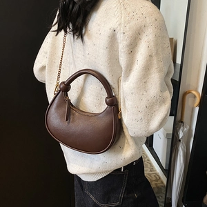 Minimalist dark brown crescent crossbody bag with knotted handle and gold chain strap
