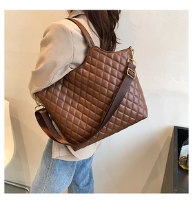 Detail of brown quilted tote bag showing leather texture and adjustable woven shoulder strap