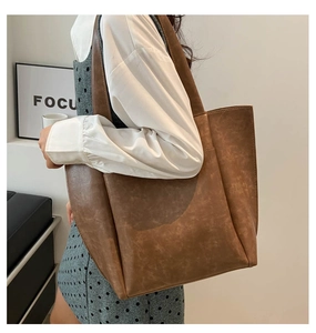 Grande borsa tote marrone indossata con texture vintage e tasca laterale esterna