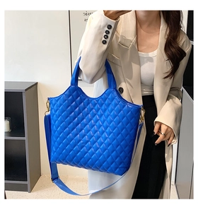 Detail view of electric blue quilted tote bag featuring gold hardware and a wide strap