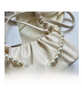 Detailed close-up of cream pleated cloud bag with elegant pearl chain and PU texture