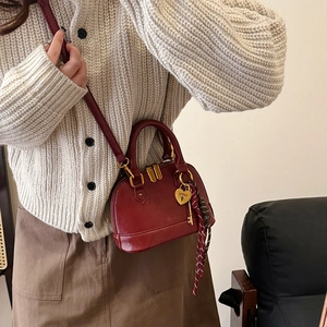 Chic burgundy shell-shaped crossbody bag with gold heart lock charm and thin strap