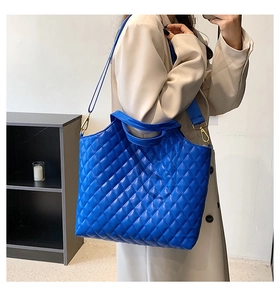Detail of blue quilted tote bag with adjustable wide fabric shoulder strap and golden buckles