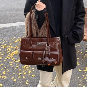 Brown vintage multi-pocket shoulder bag with silver locks on an autumn ginkgo leaf background