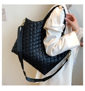 Close-up of black quilted tote bag with soft leather texture and golden metal hardware