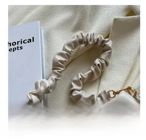 Detail shot of a creamy white cloud bag featuring soft pleated straps and gold metal hooks