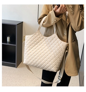 Detail of off-white quilted tote bag with golden hardware and adjustable strap