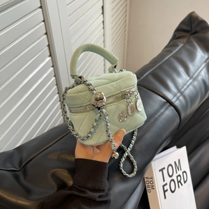 Mint green quilted mini box bag with silver chain and floral charm on a handle