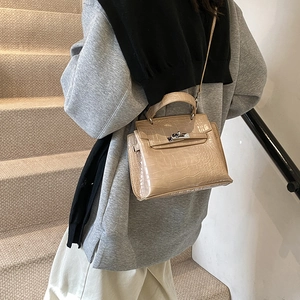 Borsa retrò beige con motivo a coccodrillo, manico e tracolla in un ambiente minimalista