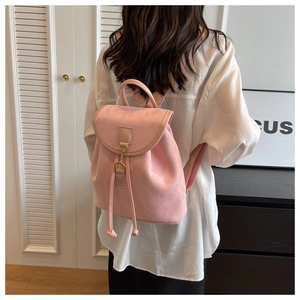 Détail d'un sac à dos en daim rose avec fermeture à cordon et boucles dorées