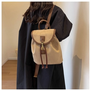 Vue détaillée d'un sac à dos en daim beige avec bordure en cuir brun porté par un mannequin