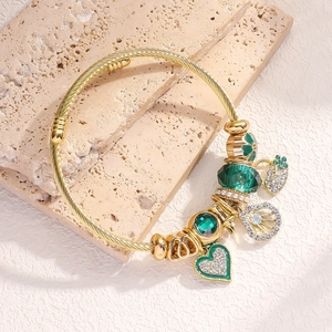 Macro shot of gold charm bracelet with green crystal beads and sparkling heart lock charm