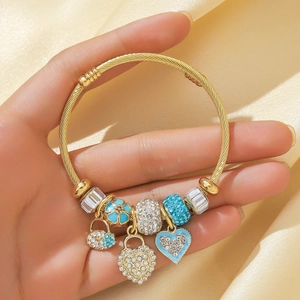 Gold cable bangle featuring heart lock pendants and blue crystal charms on silk