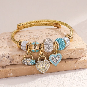Detail of a gold wire rope bracelet with heart lock charms and blue crystal beads