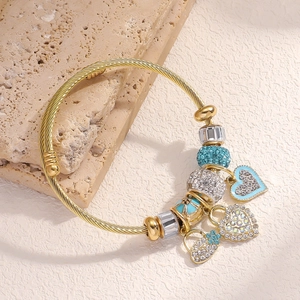 Detailed shot of golden twisted bangle with blue beads and heart-shaped crystal charms