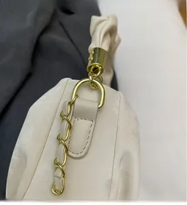 Detailed close-up of light gold metal hardware and textured beige ruched handbag strap