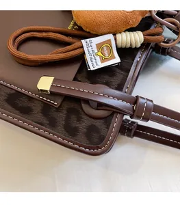 Close-up of brown leather stitching and leopard print texture with bear pendant