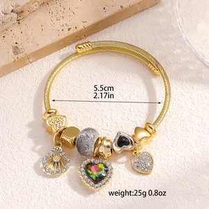 Detail view of gold charm bracelet with colorful heart gemstone and 5.5cm inner diameter size