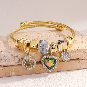 Adjustable golden spiral bracelet with rainbow crystal heart and pave charms on stone
