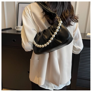 Detail of black pleated cloud bag featuring large pearl strap and soft leather texture