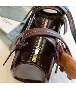 Close-up of the secure gold zipper closure and contrast stitching on dark brown leather tote