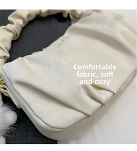 Macro shot of soft cream-colored pleated leather texture with a plush pendant detail