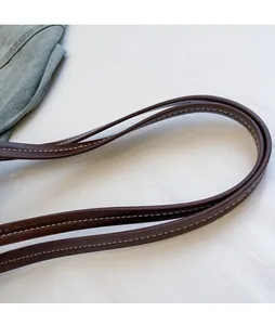 Close-up of deep brown shoulder straps with white contrast stitching on a tote bag