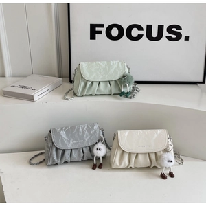 Détail de trois sacs plissés en menthe, argent et crème avec une bandoulière chaîne