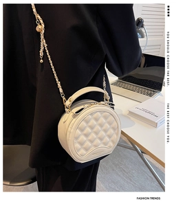 Détail du sac rond matelassé beige avec chaîne dorée et ornement sphérique élégant